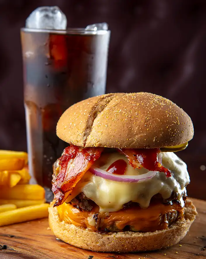 Hambúrguer artesanal premium duplo com queijo derretido, bacon crocante, cebola roxa e batata frita, servido no restaurante Tipo Prime na Chácara Santo Antônio